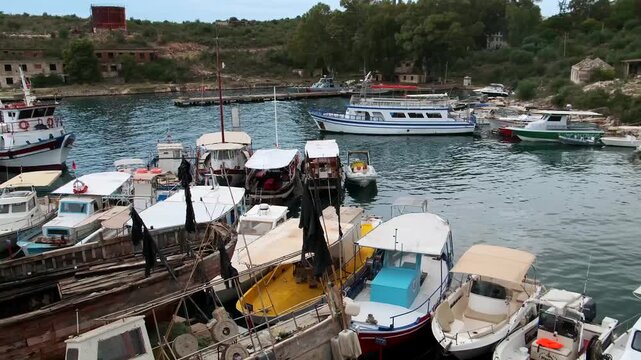 Verfallene Holzboote vor Hafenbecken mit Fischereischiffen, Saranda, Qark Vlora, Albanien