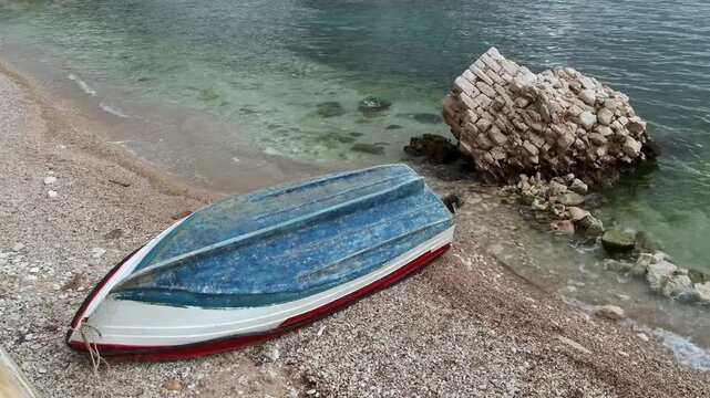 Strandboot und K&uuml;stenfelsen im seichten Wasser der Adriabucht, Saranda, Qark Vlora, Albanien