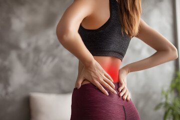Woman holding lower back in pain, illustrating backache, muscle strain, posture problems, and physical discomfort related to health and fitness.