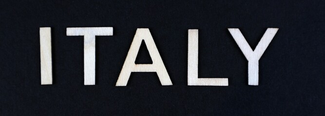 Italy written with wooden letters, Italy sign on black background for PGN and copy space.