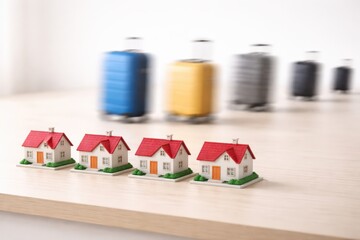 Miniature Houses Displayed with Blurred Luggage in the Background, Representing Travel and Real Estate Concepts of Movement and Stability