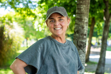 Smiling middle aged woman wearing a cap and sportswear in a sunny park