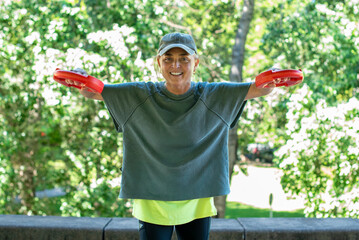 Fit middle aged woman performing weightlifting exercises during morning routine
