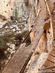 Caminito del Rey  The view into the abyss reveals the dangerous remains of the old, dilapidated concrete path directly next to the new, safe wooden walkway along the rock face.
