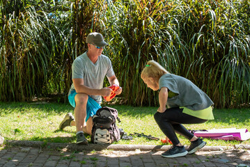 Middle aged couple organizing their sports equipment in a park after an outdoor workout