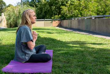 Middle aged lady in sportswear focusing on breathing exercises outdoors