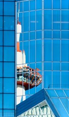 The striking red and white structure of the Kyoto Tower is reflected in the modern blue glass facade of a building. A fascinating interplay of architecture and reflection.