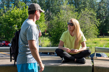 Middle aged couple talking and smiling after an outdoor workout in a sunny park
