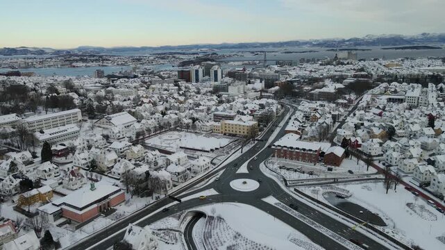 Aerial drone footage showing vehicle traffic moving through an urban area in Stavanger, Norway during winter. The scene captures roads, surrounding buildings, and typical city infrastructure under col