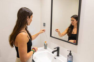 Young woman examining a small test stick while reflecting in a modern bathroom mirror