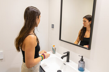 Woman applying toothpaste to brush in a clean, modern bathroom during her daily routine