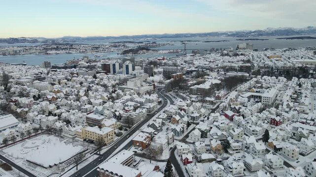 Aerial drone footage showing an urban neighborhood in Stavanger, Norway covered in snow during winter. The scene includes residential buildings, streets, and surrounding infrastructure, documenting ty