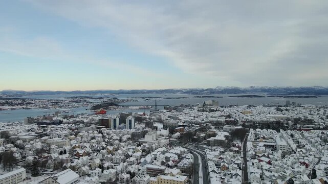 Aerial drone footage showing an urban neighborhood in Stavanger, Norway covered in snow during winter. The scene includes residential buildings, streets, and surrounding infrastructure, documenting ty