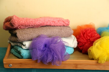 Towels and bath sponges arranged on a wooden shelf in a bathroom during the day