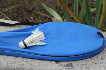 Badminton racket and shuttlecock on a blue cover outdoors