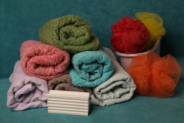 Cotton towels and bath accessories on a blue background with soap and bath sponges arranged neatly