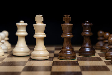 Close up of Kings in center of game board backed by the queens. Concept of CEO leadership power struggle