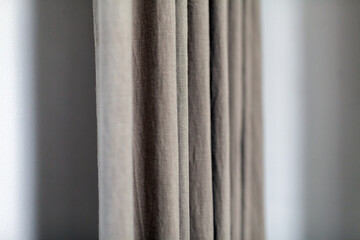 Fototapeta premium Soft, textured fabric curtains in neutral tones gently draping against a light wall, creating a serene atmosphere and enhancing interior decor aesthetics