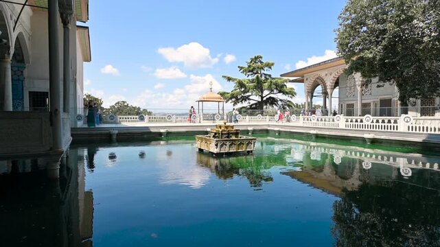 Istanbul, turkey, august 1, 2025. Beautiful view of the historic topkapi palace courtyard pool and fountain in istanbul, turkey, with tourists walking in the background