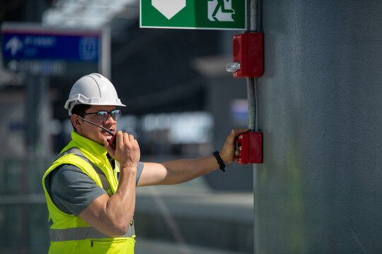 Engineer wearing safety unifrom and helmet under checking fire alarm emergency system in industry factory and exit door is factory security protection concept.	