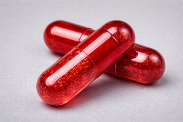 Red capsule supplements isolated on neutral background