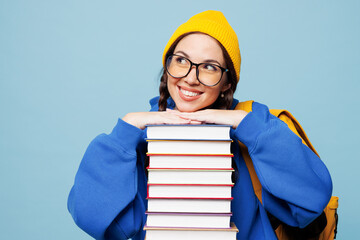 Young smiling cheerful happy smart woman reader student she wear casual clothes hold stand behind stack of books isolated on pastel plain light blue color background. High college lifestyle concept.