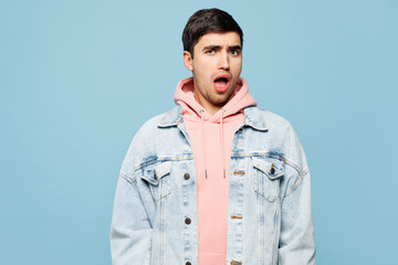 Obraz premium Young sad shocked dissatisfied anxious indignant mad man he wearing pink hoody denim casual clothes look camera isolated on plain pastel light blue cyan background studio portrait. Lifestyle concept.