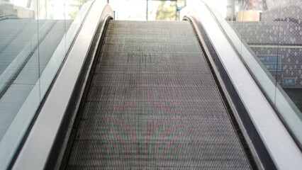 Obraz premium Escalator moving upwards in modern urban environment with glass panels