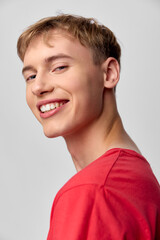 Young man with a bright smile in a red shirt, casual studio headshot showing happiness, friendly and confident vibe with relaxed posture and natural lighting
