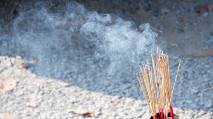 The incense is lit, and smoke billows upward.