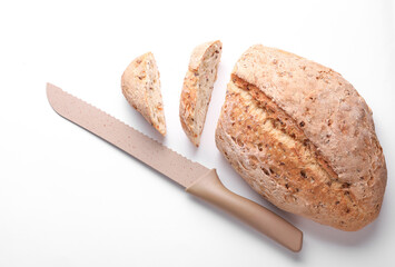 Slices of grain bread and knife on white background. Top view