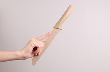 Ceramic kitchen knife in female hand on a gray backgroun