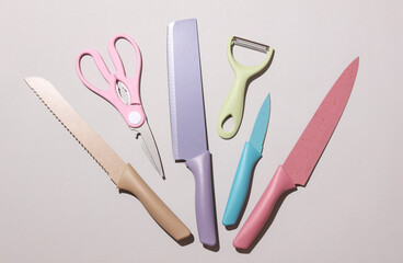 Set of colored kitchen ceramic knives and scissors on gray background. Top view. Flat lay