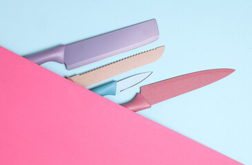 Colored kitchen ceramic knives on pink blue background. Top view. Flat lay
