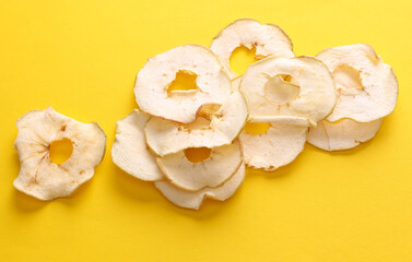 Slices of dry apple chips on yellow background