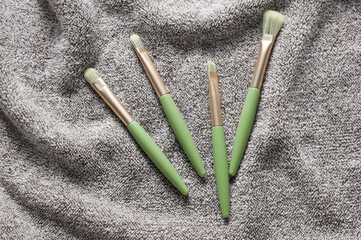 Makeup brushes on gray wavy fabric towel