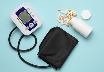 Electronic medical tonometer for measuring blood pressure with pills on a blue background. Top view. Flat lay