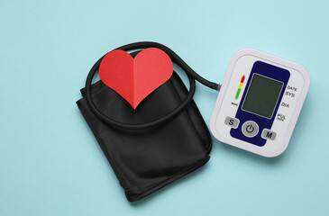 Electronic medical tonometer for measuring blood pressure and red heart on a blue background. Heart Health Monitoring. Top view