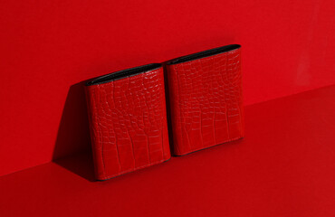 Red crocodile leather wallets on red background.