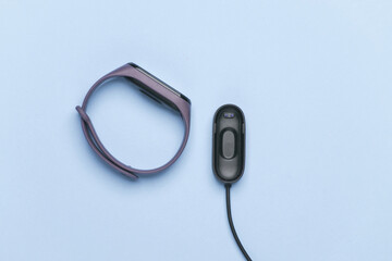 Smart bracelet with charger on blue background