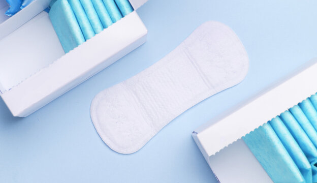 Box with sanitary pads on blue background. Feminine hygiene