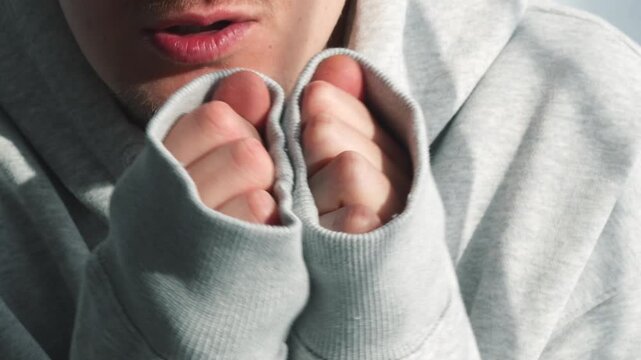 A freezing man in a long-sleeved sweater.
A warmly dressed man warms himself in low temperatures.