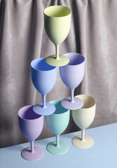 Colored Plastic glasses against the background of a curtain. Aesthetic still life. Minimalism. Holiday, party mood