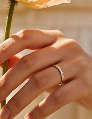 Macro Close-Up of Hand Holding Flower Stem with Plain Ring Visible, Romantic Lifestyle Concept for Love, Wedding Symbolism, Minimal Jewelry Branding, Soft Emotion, and Premium Visual Storytelling