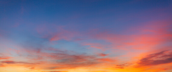 Fototapeta premium Vibrant Panoramic Sunset Sky with Dramatic Pink and Orange Clouds,A breathtaking panoramic view of a sunset sky featuring a vivid transition from deep blue to brilliant orange and pink hues,