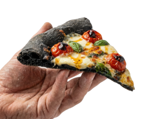 A hand holds a slice of black pizza topped with cheese, cherry tomatoes, and basil, showcasing a unique culinary creation against a dark background.