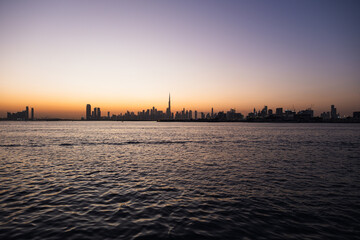 Fototapeta premium Dubai city skyline with creek boats and waterfront location at sunset, 4k background wallpaper for real estate and Dubai luxury lifestyle
