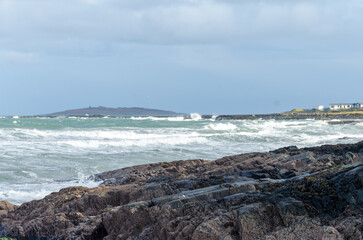 Rough incoming tide at Groomsport beach with rocks in the foreground
