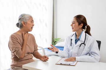 Young doctor talking with senior woman during physical examination, discussing symptoms and...