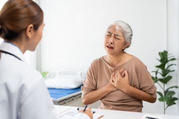 Senior woman suffering from severe chest pain during a medical consultation, with doctor providing...